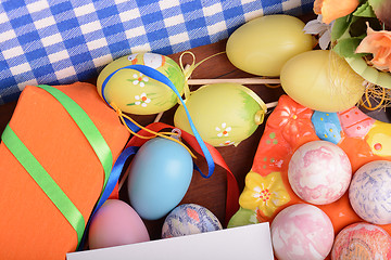 Image showing Easter background with colorful eggs and yellow tulips over white wood. Top view with copy space