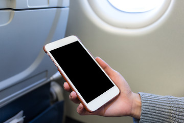 Image showing Holding digital mobile phone at airplane