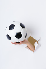 Image showing Hand through the hole in paper with soccer ball