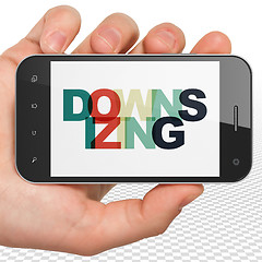 Image showing Finance concept: Hand Holding Smartphone with Downsizing on  display