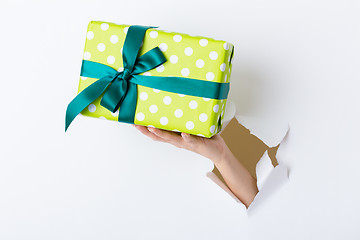 Image showing Hand through the hole in paper with present box