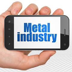 Image showing Manufacuring concept: Hand Holding Smartphone with Metal Industry on display