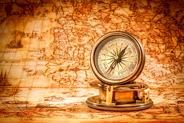 Image showing Vintage compass lies on an ancient world map.