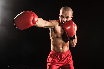 Image showing The young man kickboxing on black