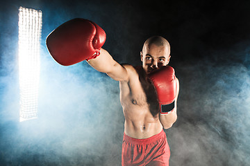 Image showing The young man kickboxing in blue smoke