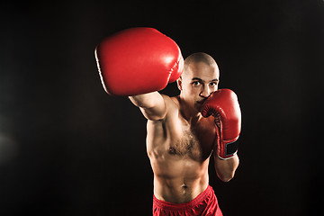 Image showing The young man kickboxing on black