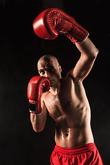 Image showing The young man kickboxing on black