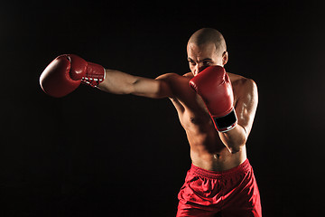 Image showing The young man kickboxing on black