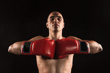 Image showing The young man kickboxing on black