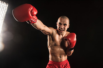 Image showing The young man kickboxing on black