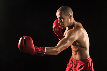 Image showing The young man kickboxing on black