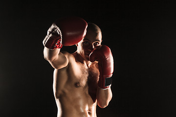 Image showing The young man kickboxing on black