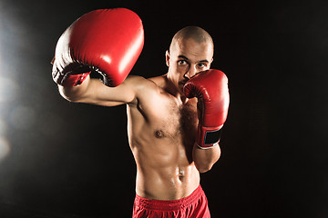 Image showing The young man kickboxing on black