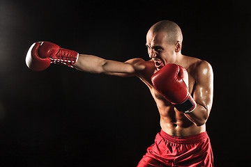 Image showing The young man kickboxing on black