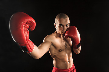 Image showing The young man kickboxing on black