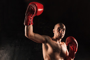 Image showing The young man kickboxing on black