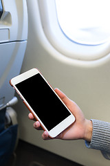 Image showing Woman holding digital mobile phone at airplane