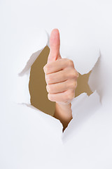 Image showing Hand through the hole in paper with woman thumb up