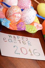 Image showing Easter with eggs in nest and yellow tulips over wooden table. 