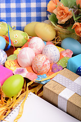 Image showing Easter background with colorful eggs and yellow tulips over white wood. Top view with copy space