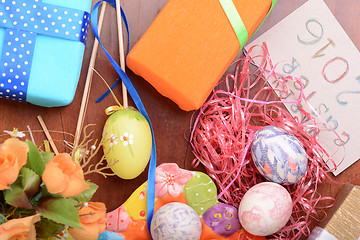 Image showing Easter with eggs in nest and yellow tulips over blue wooden table. Top view
