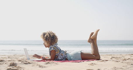 Image showing Happy Woman Typing On A Laptop On A Beach