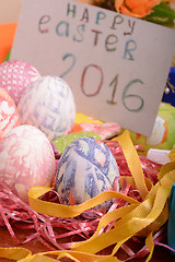 Image showing Easter with eggs in nest and yellow tulips over blue wooden table. Top view