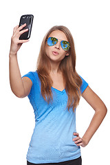 Image showing Woman in sunglasses with tropical resort reflection making selfie with smartphone