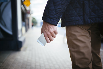 Image showing Young men holding smartphone in hand on the street