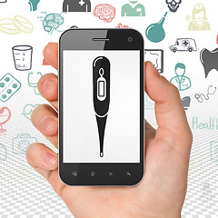 Image showing Health concept: Hand Holding Smartphone with Thermometer on display