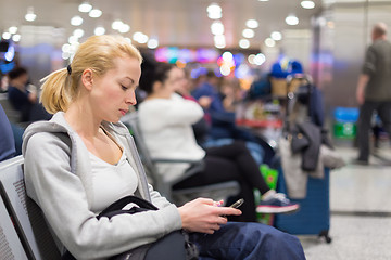 Image showing Female traveler using cell phone while waiting.