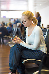 Image showing Female traveler using cell phone while waiting.