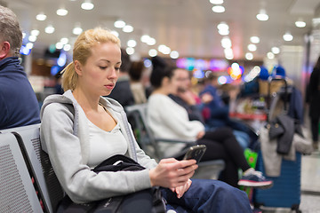 Image showing Female traveler using cell phone while waiting.