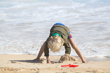 Image showing Boy playing with toys on beach.