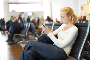 Image showing Female traveler using cell phone while waiting.