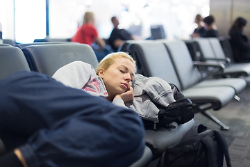 Image showing Tired female traveler sleeping on airport.