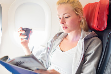 Image showing Woman reading magazine on airplane.