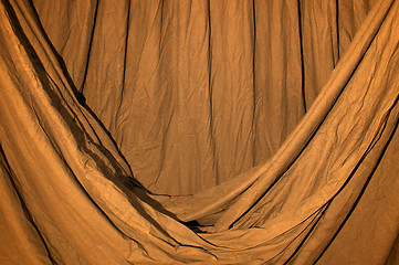 Image showing Draped black background cloth lit with orange gel