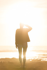 Image showing Woman on sandy beach watching sunset.