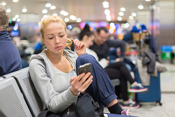 Image showing Female traveler using cell phone while waiting.