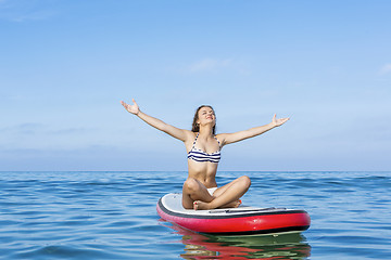 Image showing Woman relaxing over a paddle surfboard