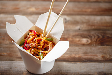 Image showing Noodles with pork and vegetables in take-out box on wooden table