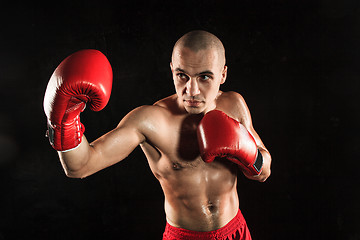 Image showing The young man kickboxing on black