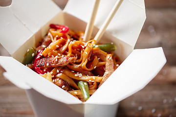 Image showing Noodles with pork and vegetables in take-out box on wooden table