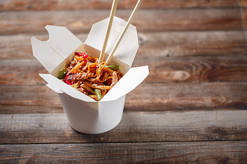 Image showing Noodles with pork and vegetables in take-out box on wooden table