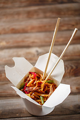 Image showing Noodles with pork and vegetables in take-out box on wooden table