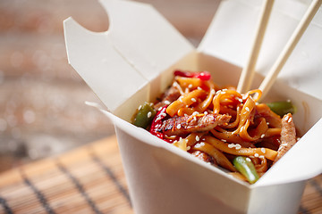 Image showing Noodles with pork and vegetables in take-out box on wooden table