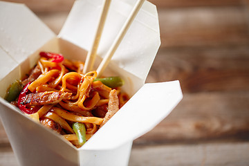 Image showing Noodles with pork and vegetables in take-out box on wooden table