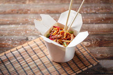 Image showing Noodles with pork and vegetables in take-out box on wooden table