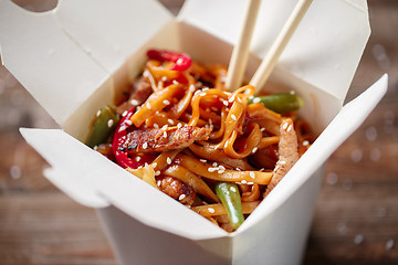 Image showing Noodles with pork and vegetables in take-out box on wooden table